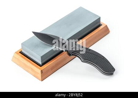 Folding pocket knife laying on a whetstone Stock Photo