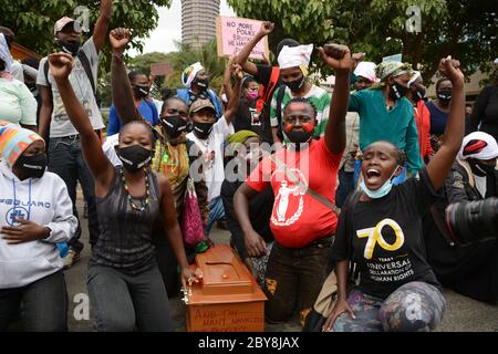 Nairobi, Kenya. 09th June, 2020. Residents of Mathare slums are seen outside parliament building with their fists raised high while having an empty coffin during the demonstrations.Residents of Mathare slums demonstrate outside the parliament building in a protest against police killings and brutality in the area while wearing facemasks with names of those who had been killed by police. Credit: SOPA Images Limited/Alamy Live News Stock Photo