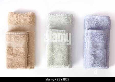 Folded terry towels isolated over the white background, set of three color versions. Top view Stock Photo