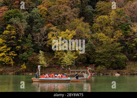 Kyoto / Japan - November 12, 2017: People enjoying traditional boat ride down the Katsura River near Arashiyama park in Kyoto, Japan Stock Photo