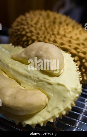 Durian fruit cut in half on a wooden table. The durian is the edible ...