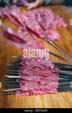 Metal sticks with pork and beef raw meat pieces to be fried for kebabs to sell on the street in the Muslim Quarter, Xian town, China Stock Photo