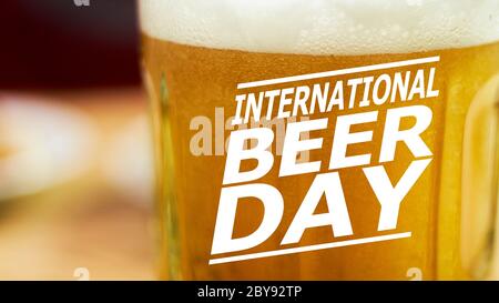 Close-up view of beer glass with text overlay on it - International beer day. Glass of cold light beer with bubble froth in glass. Drink alcohol Stock Photo