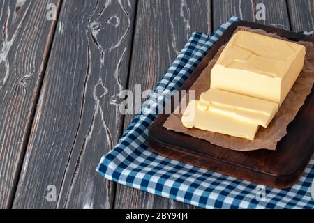 Wooden board with butter on blue checkered napkin Stock Photo