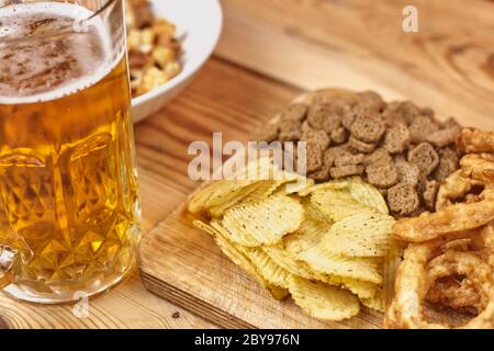 A glass of beer and different snacks on the table. Celebrating international beer day or Octoberfest. Drinking beer after a hard working day or week Stock Photo