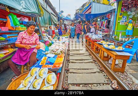 MAEKLONG, THAILAND - MAY 13, 2019: The fruit stall in Maeklong Railway Market with packed slices of fresh durian, papaya, mango and greens, on May 13 Stock Photo