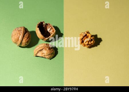 Peeled nut along with its shells and another nut in shell on green and yellow background Stock Photo