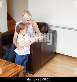 Girl holding a remote control standing in the living room Stock Photo
