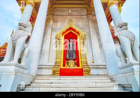 The statue of Buddha on the backside of Wat Benchamabophit Dusitvanaram Marble Temple is guarded by two stone singha lions, Bangkok, Thailand Stock Photo