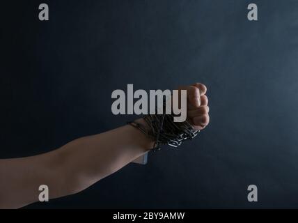 Fist of Hand are chained in chains on the black background, concept of
