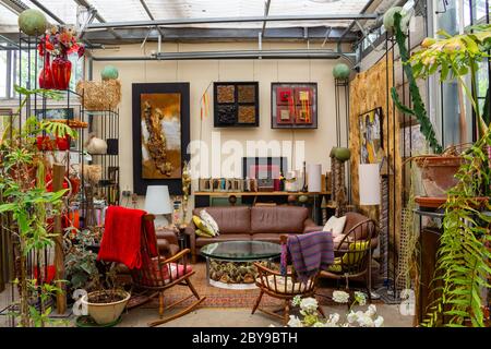 Living room in a greenhouse behind a garage door, interior living room with artwork and plants Stock Photo