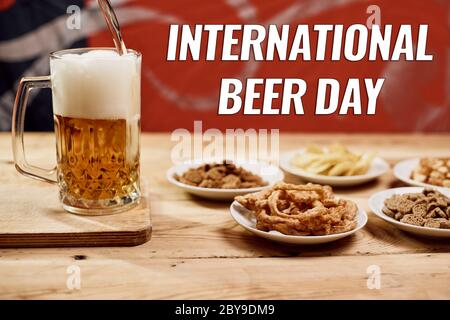 A glass of beer and different snacks on the table. Celebrating international beer day or Octoberfest. Drinking beer after a hard working day or week Stock Photo