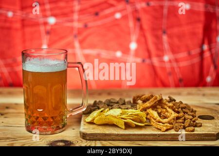 A glass of beer and different snacks on the table. Celebrating international beer day or Octoberfest. Drinking beer after a hard working day or week Stock Photo