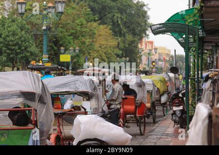 Rickshaws waiting in line on Malioboro street jalan in Yogyakarta, Yogya, Java, Indonesia. Becak taxi with one horse drivers waiting for tourists to t Stock Photo