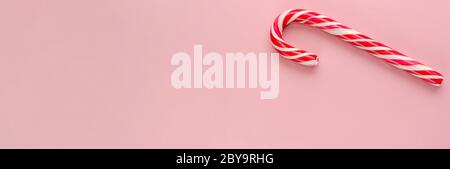 Single candy cane on pink background. Banner. Sweet Christmas symbol. Candy Cane Day concept. Top view. Copy space Stock Photo