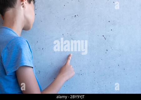 Upset sad boy stand alone and leaning on the wall. Learning difficulties, family problems, bullying, depression, stress or frustration concept Stock Photo