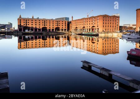 Red brick buildings, former warehouses reflected in the water, Albert Dock, Liverpool Stock Photo