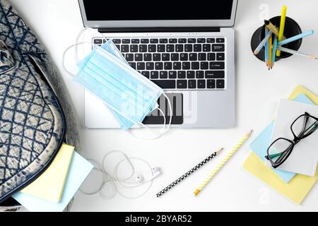 Modern laptop with backpack and stationery on white table Stock Photo