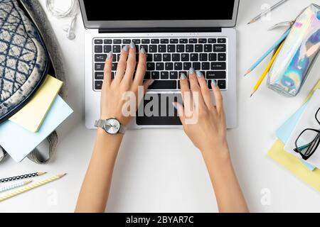 Females hands working on modern laptop with backpack and stationery Stock Photo