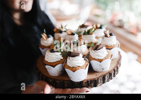 Many cupcakes decorated with cream and berries on the piece of wood. Wedding cupcakes Stock Photo