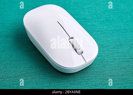 Wireless computer mouse made of white plastic on a green background, close-up. Stock Photo