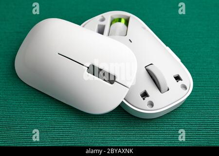 Wireless computer mouse with a magnetic cover. Disassembled input device in white on a green background. Stock Photo