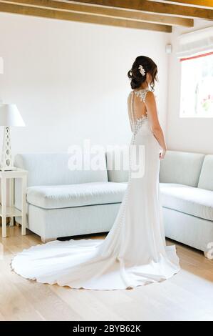 Bride looking out of window and fanned out wedding dress Stock Photo