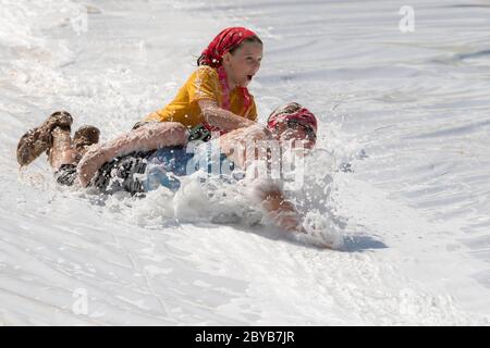 Poley Mountain, New Brunswick, Canada - June 10, 2017: Participating in the annual fundraiser 'Mud Run For Heart'. A woman and child slide down a foam Stock Photo