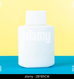 Nameless white cosmetic product bottle on blue and yellow background Stock Photo