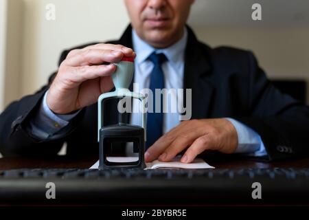 Close up. The airport employee checks the passports of passengers boarding the aircraft. He looks at his passport and stamps it. Stock Photo