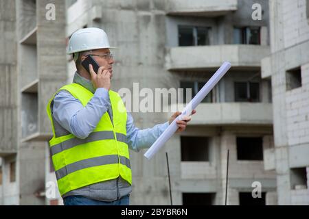 Engineer Working on Building Site  and giving Tasks over the Phone Stock Photo