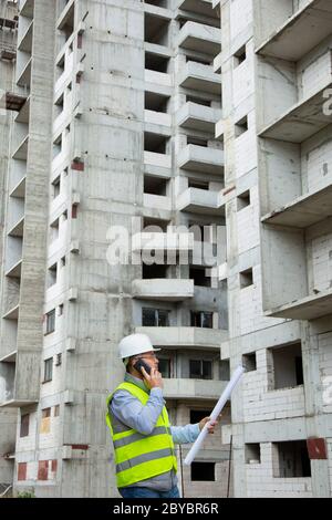 Senior Engineer Working on Building Site  and giving Tasks over the Phone Stock Photo