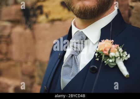 Close up of tie knot. Groom in blue suit with wedding boutonniere. Shallow depth of field. Copy space. Stock Photo