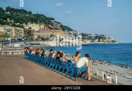 sightseers enjoy the view over the Baie des Anges, the 'Bay of the Angels' at Ponchettes Beach at the Nice waterfront, French Riviera, Provence-Alpes- Stock Photo