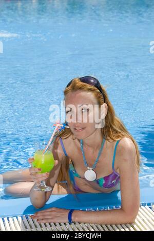 Beautiful woman with cocktail in pool. Stock Photo