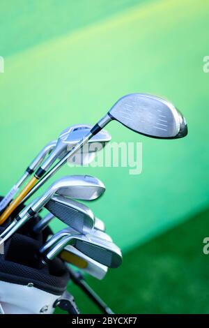 Closeup shot of variety of golf clubs in bag on green background Stock Photo