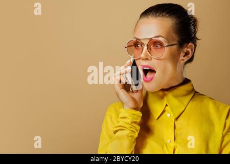 Closeup portrait of attractive caucasian business lady wearing colorful yellow shirt isolated on beige background in studio Stock Photo
