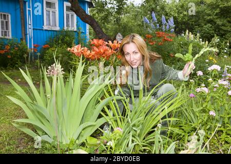 Young pretty woman looks after behind plants in th Stock Photo