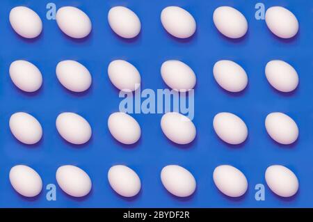 White eggs arranged on solid color background Stock Photo