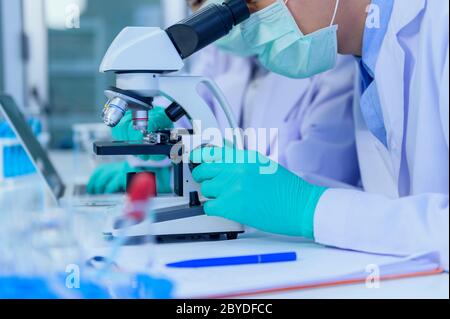 Scientist team has researching and working on Coronavirus cure in the laboratory. Asian Doctor examining samples and applying a vaccine against virus Stock Photo
