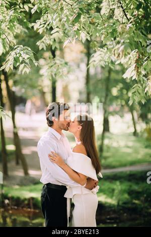 Just-Married Couple Kissing During Ceremony Without Guests In Nature Park Stock Photo