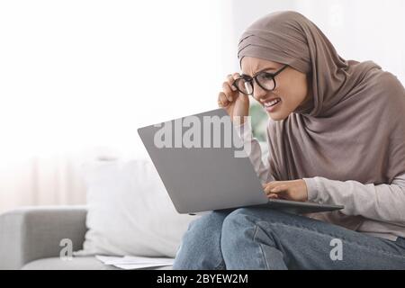 Eyesight Problems. Woman In Hijab Squinting Eyes While Looking At Laptop Screen Stock Photo