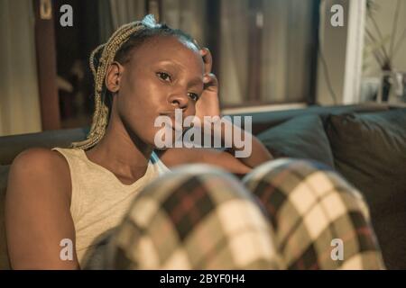young African American woman suffering depression - sad and depressed black teenager girl in pain at home sofa couch feeling overwhelmed and emotional Stock Photo