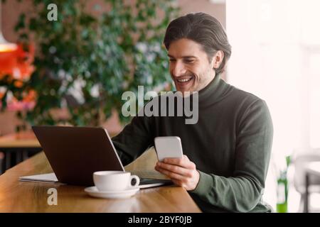 Emotional entrepreneur working online, using laptop and smartphone Stock Photo