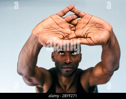 A man doing yoga in a white room. Stock Photo