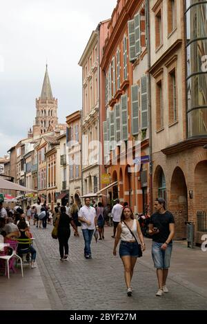 The city street of Toulouse with bell tower of Basilica of St.Sernin Basilique Saint-Sernin in the background. Toulouse.Haute-Garonne.Occitanie.France Stock Photo