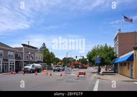 Road closed signs and cones, construction crew and excavators working on street in Windsor, Sonoma County, California, USA. Stock Photo