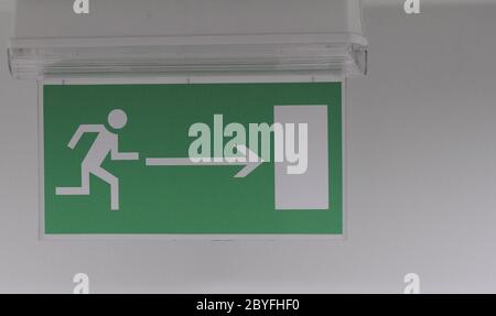 Emergency exit sign in a building glowing green Stock Photo
