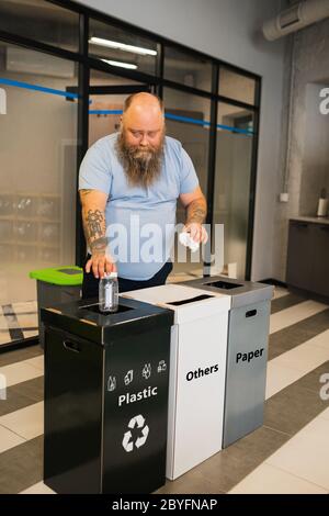 Overweight office worker throwing out sorted waste. Stock Photo