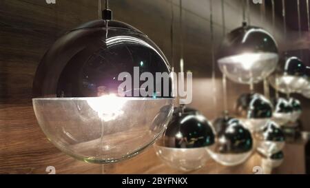 A lot of round lamps near a wooden brown wall. Round lights in the interior. Background for design. Decorative light bulbs Stock Photo